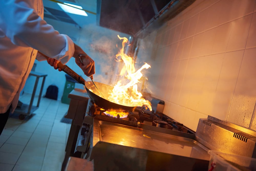 chef in hotel kitchen prepare vegetable  food with fire